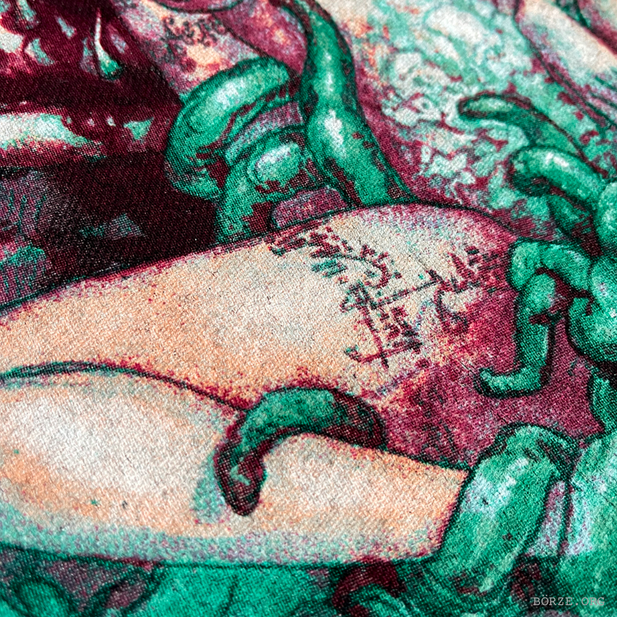 Close-up of a textured fabric with green floral patterns and a brand logo.
